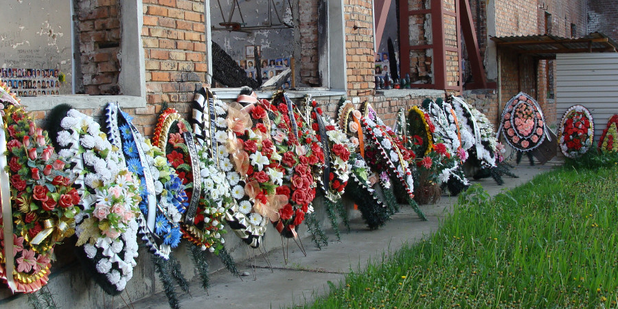 Corone di fiori attorno ai resti della palestra di Beslan