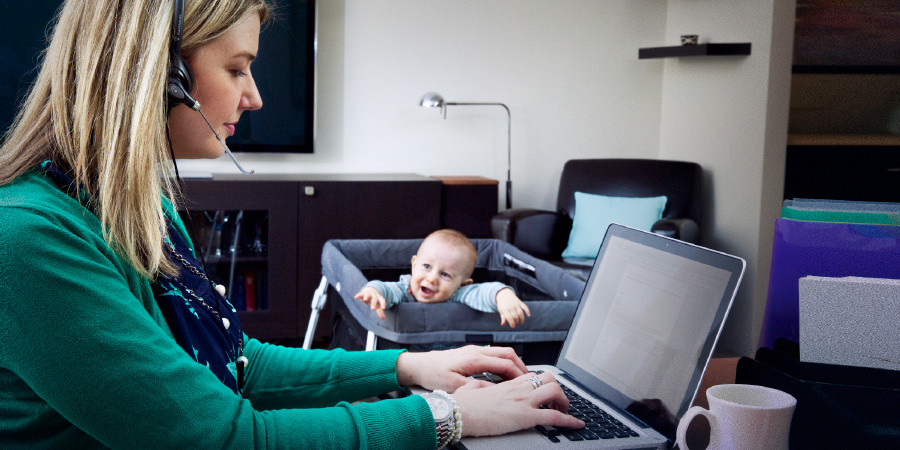 Madre lavora al computer mentre il suo bambino cerca di attirare l’attenzione