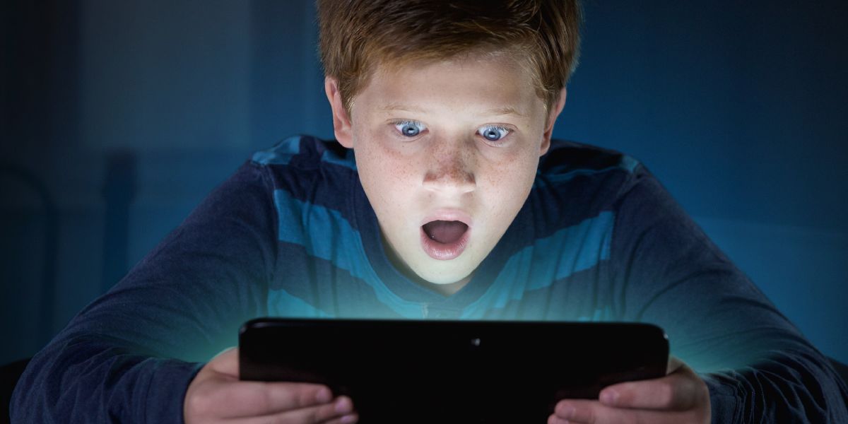 Un ragazzo è sbalordito per quello che vede sul suo dispositivo elettronico