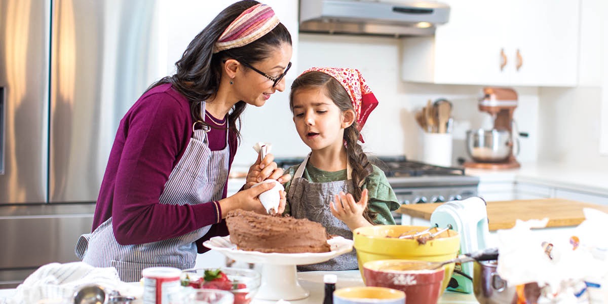 Una mamma aiuta la figlia che è dispiaciuta perché la torta che ha preparato non è venuta bene