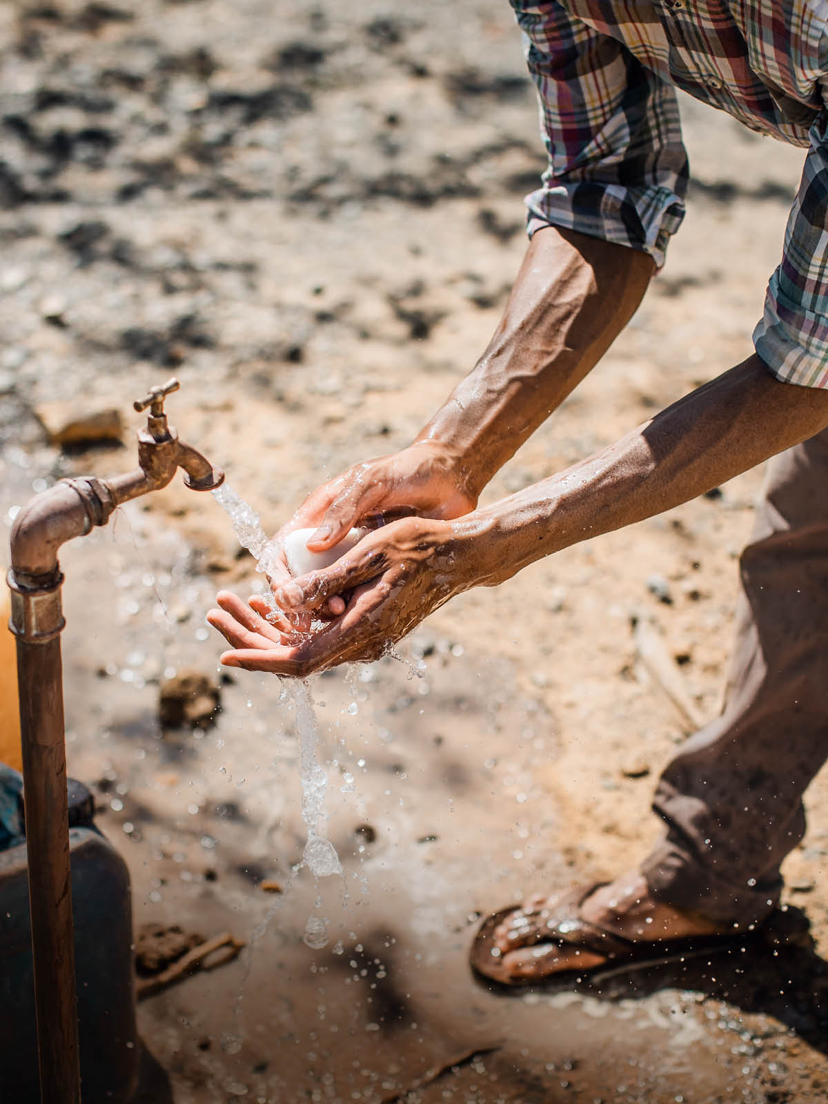Un uomo si lava le mani all’aperto con acqua e sapone.