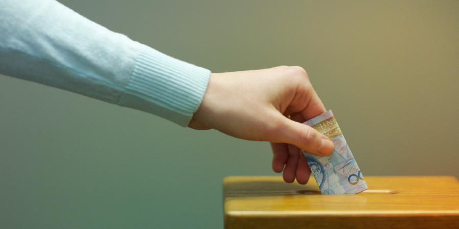Una persona fa un’offerta in una cassetta delle contribuzioni