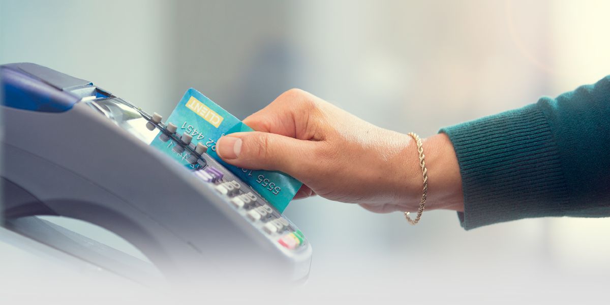 Una donna passa una carta bancaria in un terminale di pagamento