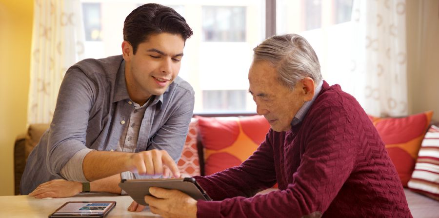 Un fratello giovane mostra a un fratello avanti negli anni come usare il suo dispositivo elettronico