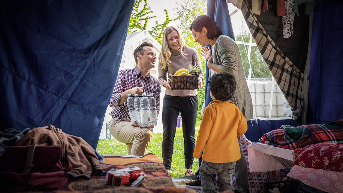 Un coppia porta cibo e altri generi di prima necessità a una madre e a suo figlio, che vivono temporaneamente in una tenda.