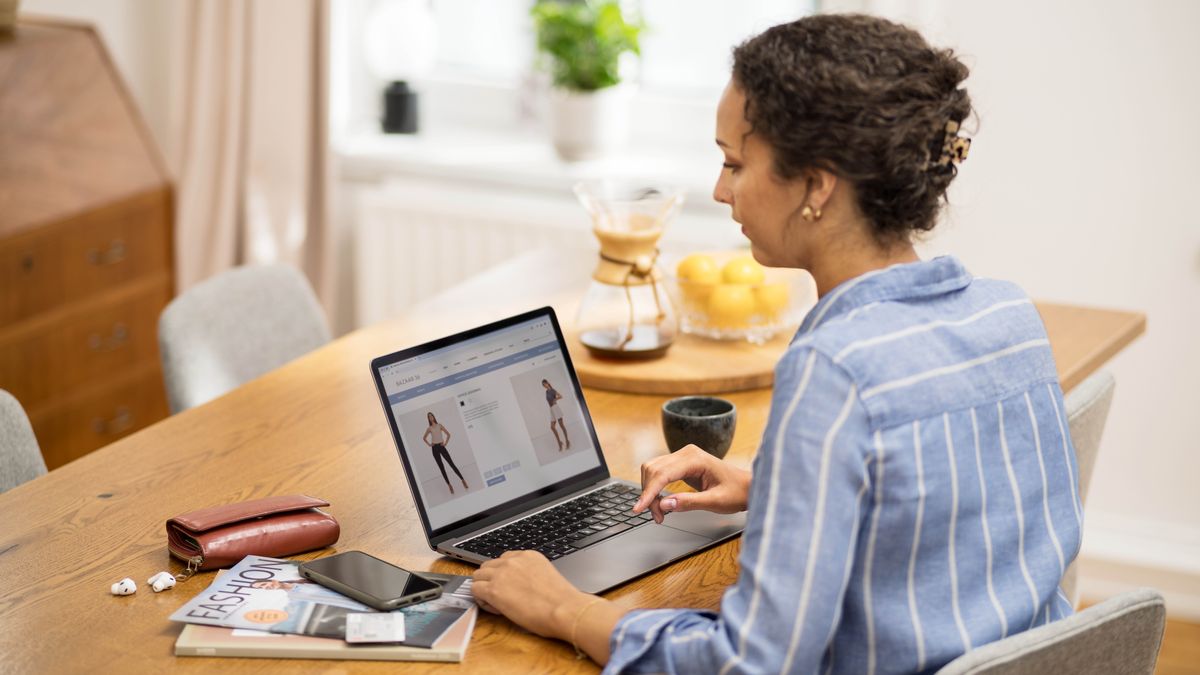 Una sorella cerca online dei capi d’abbigliamento che siano modesti. Accanto al computer ci sono delle riviste di moda.