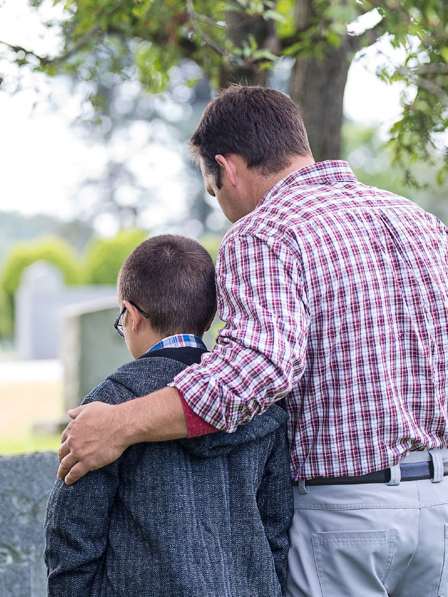 Un padre e il suo bambino davanti a una tomba