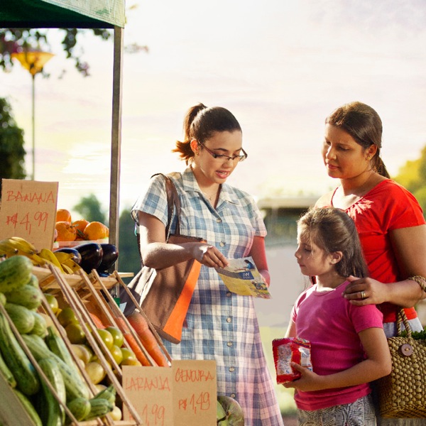 Una testimone di Geova dà testimonianza vicino a un banco di frutta e verdura