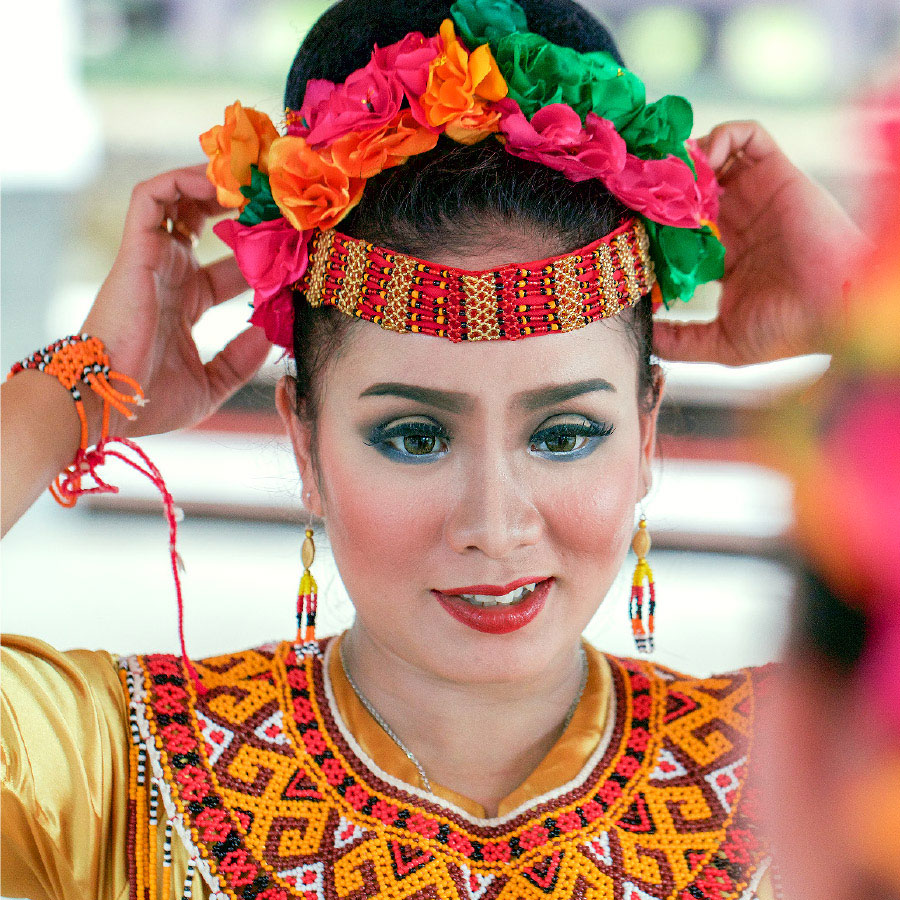 Una donna indonesiana mette sulla testa una fascia ornamentale tradizionale