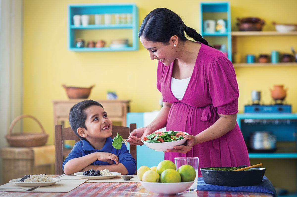妊娠中の女性が，自分と幼い息子に健康に良い食事を出している。