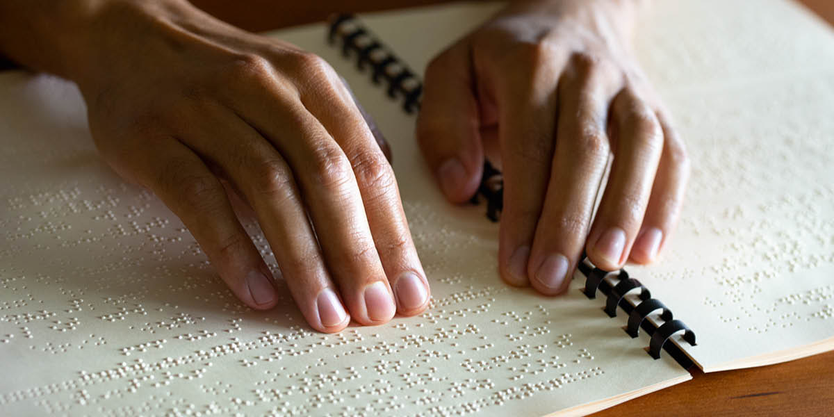 Wong wédok maca buku nganggo huruf braille.