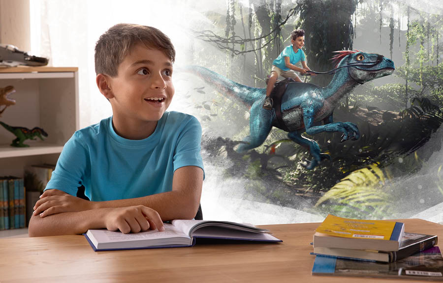 Cah lanang lagi maca buku, terus mbayangké lagi numpak dinosaurus.