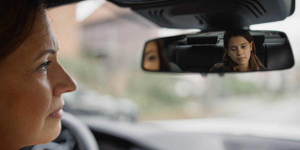 Ibu ndeloki anaké wédok sing lagi sedhih saka kaca spion.