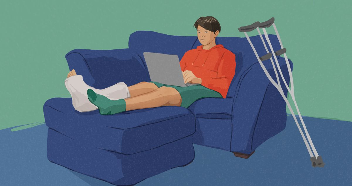 Cah lanang lagi lungguh ing sofa karo dolanan laptop. Salah siji sikilé di-gips.