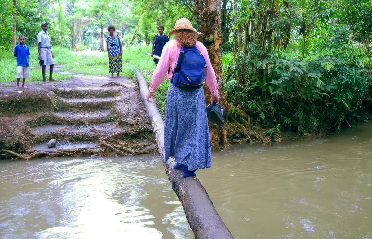 Leann mlaku ing ndhuwur kayu kanggo nyebrangi kali.