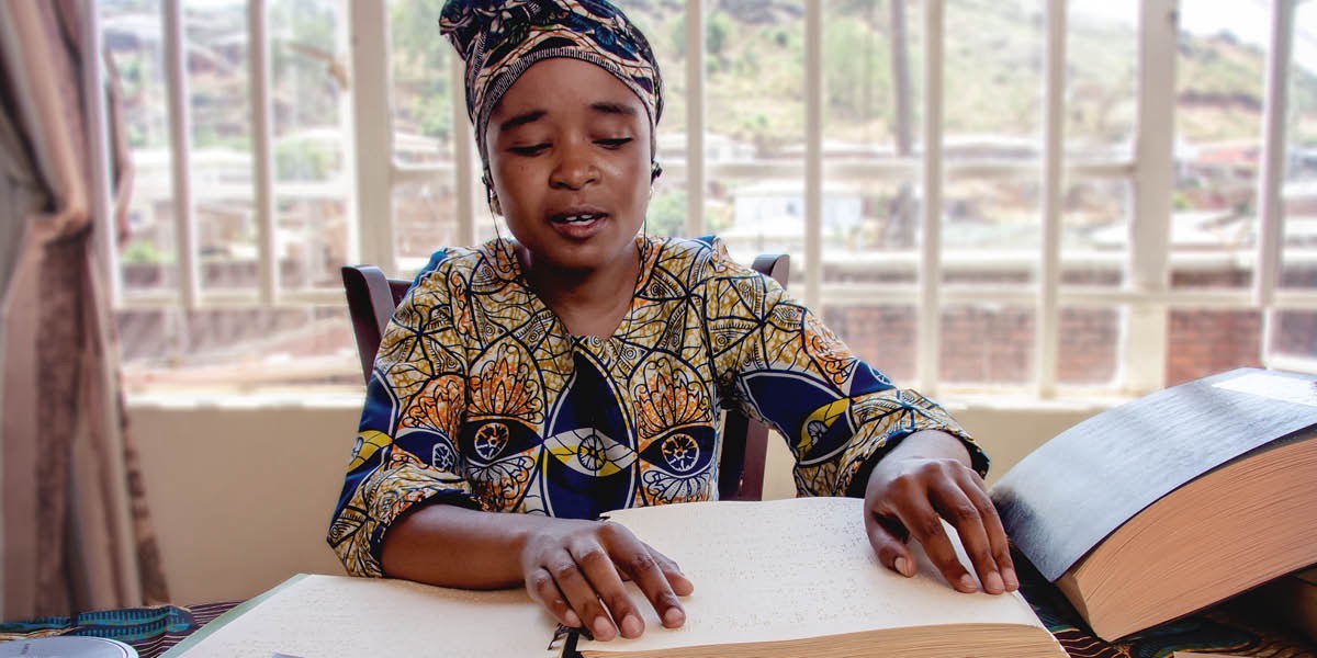 Sedulur wédok sing wuta nggunakké tangané kanggo maca publikasi braille.