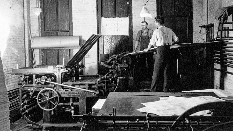 Sedulur lanang loro lagi nggunakké mesin flatbed press.