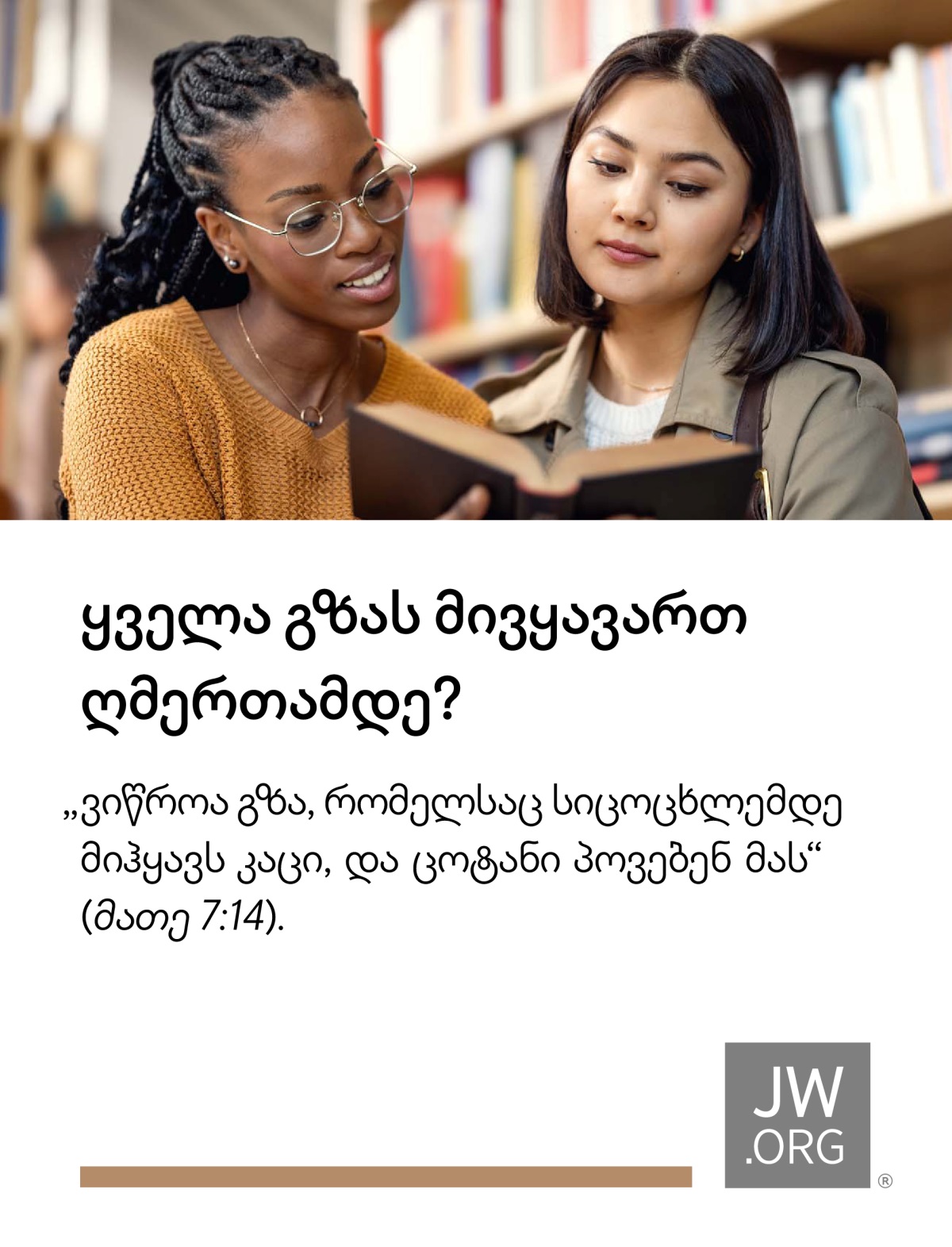 ორი ახალგაზრდა ქალი ბიბლიოთეკაში წიგნს ათვალიერებს.