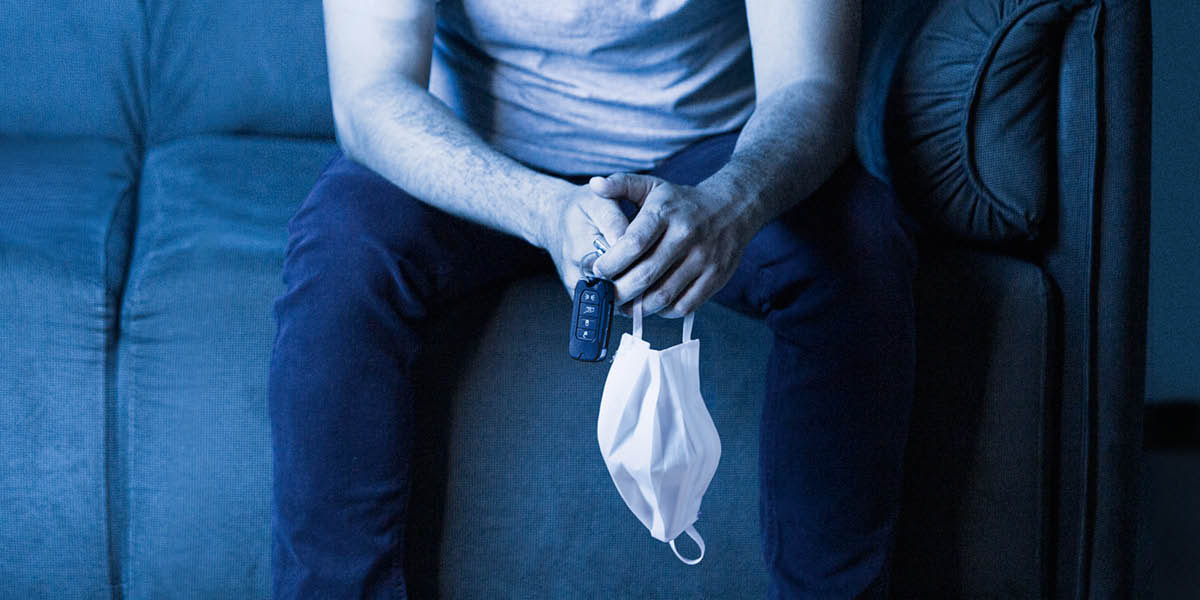 მამაკაცი სავარძელში ზის და ხელში უჭირავს მანქანის გასაღები და პირბადე.