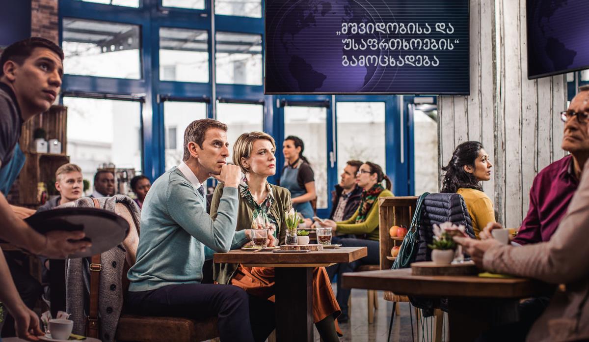 კაფეში ხალხი გაოცებული უსმენს ახალ ამბებს, სადაც „მშვიდობისა და უსაფრთხოების“ შესახებ საგანგებო განცხადება კეთდება. იეჰოვას მოწმე წყვილი არ ტყუვდება ამ ინფორმაციით