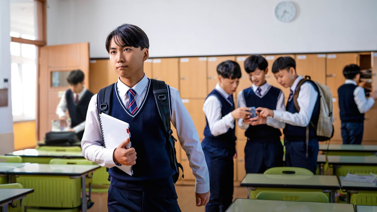 학교에서 한 청소년 형제가 휴대폰으로 무언가를 보고 있는 반 친구들에게 등을 돌리고 확신에 찬 모습으로 걸어갑니다.