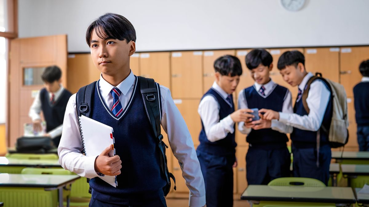 학생들이 놀란 표정으로 스마트폰에서 무언가를 보고 있는데, 한 청소년 형제가 그 자리를 떠나고 있습니다.