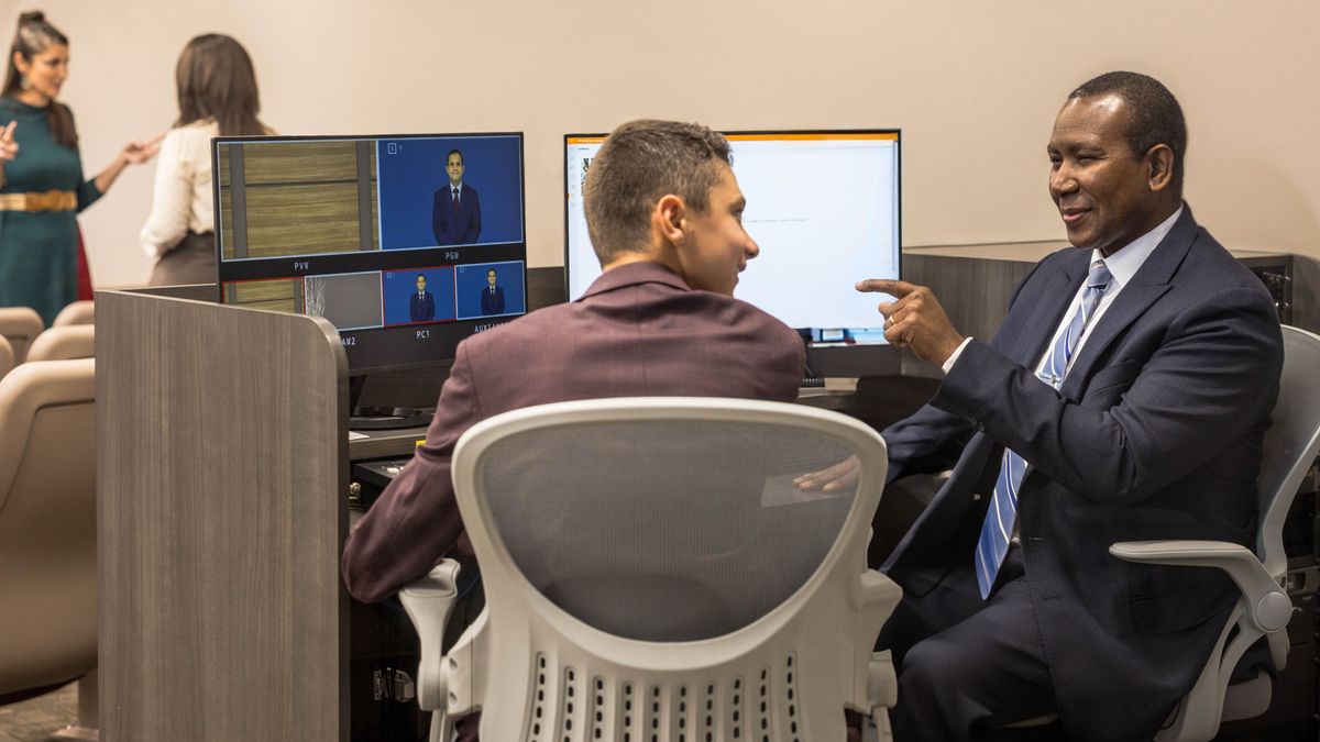 한 장로가 왕국회관에서 무선 마이크의 배터리를 교체하는 방법을 청소년 형제에게 알려 주고 있습니다.