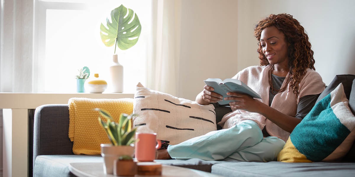 Omukazi ng’ali mu ntebe ng’asoma Bayibuli.