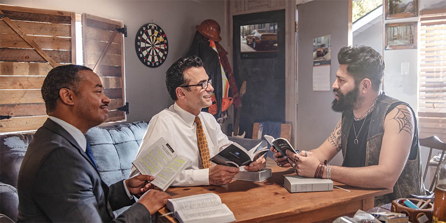 Ab’oluganda babiri nga bayigiriza Bayibuli omusajja eyeekubye tatu ennyingi era ayambadde omukuufu n’obukomo