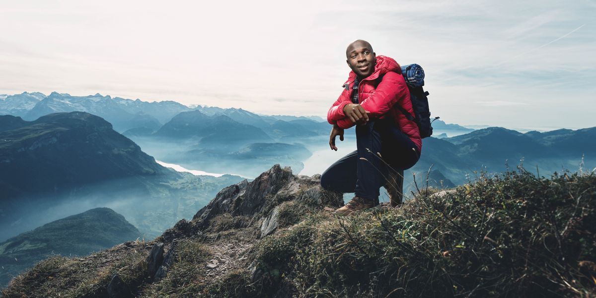 Omuvubuka alagiddwa mu bitundu ebivuddeko ng’atuuse ku ntikko y’olusozi, era nga musanyufu.