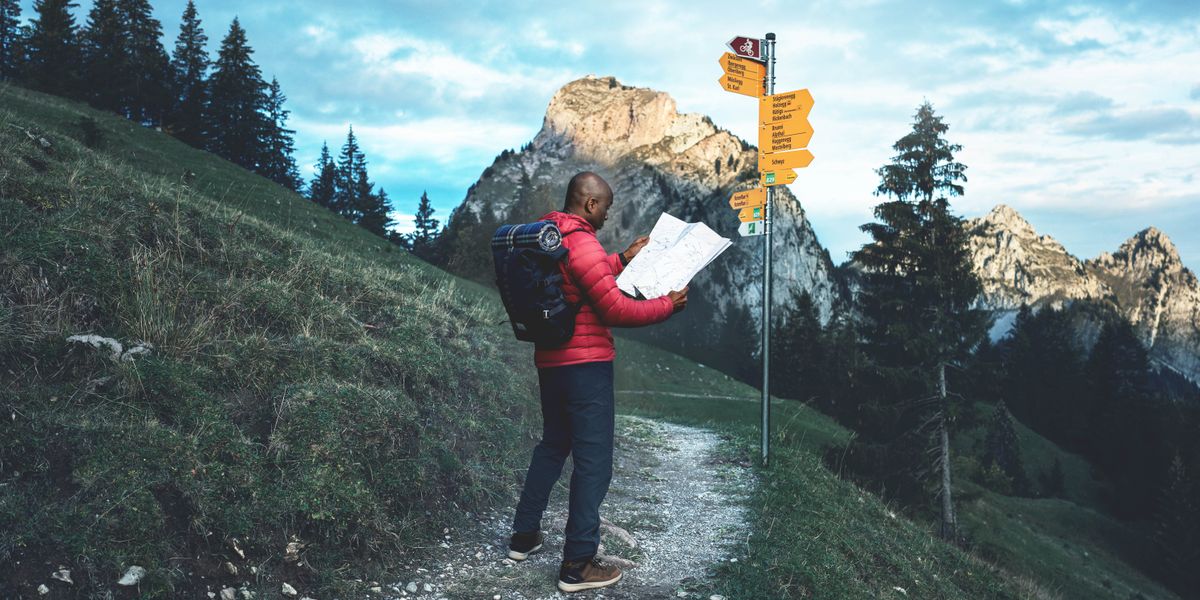 Omuvubuka alagiddwa mu bitundu ebivuddeko ng’ali ku lusozi era nga yeetegereza mmaapu. Mu maaso waliwo obupande obuliko obubonero obutali bumu obusonga mu bifo eby’enjawulo, era waliyo n’olusozi.