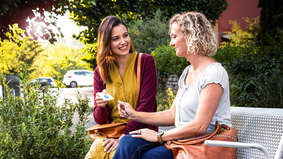 La sœur prêche à une dame assise à côté d’elle sur un banc public.