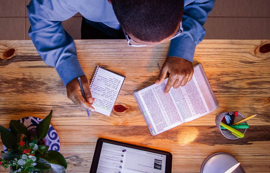 The same younger brother preparing for telephone witnessing by looking up scriptures and writing brief notes.