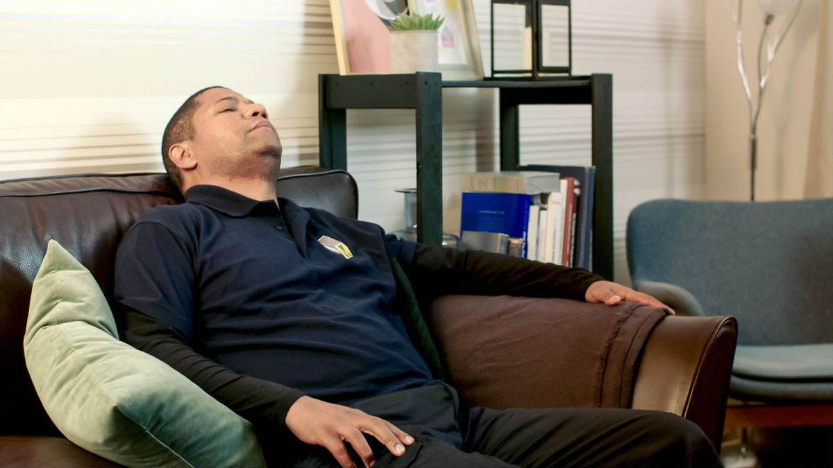 A scene from the video “Display Unfailing Love in the Ministry.” The father from the video falls asleep on a sofa after coming home from work.