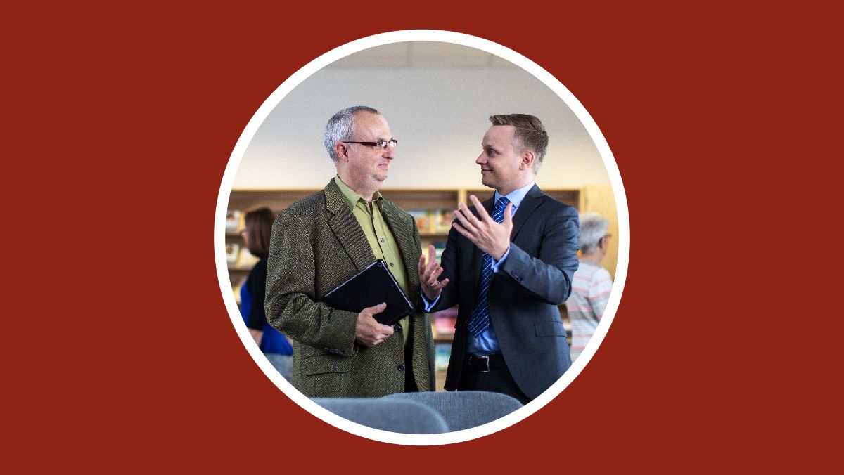 A brother with his Bible student at the Kingdom Hall, explaining what happens at Christian meetings.