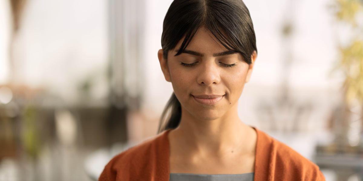 Un mucha muher ta haci oracion den un ambiente trankil na su cas.
