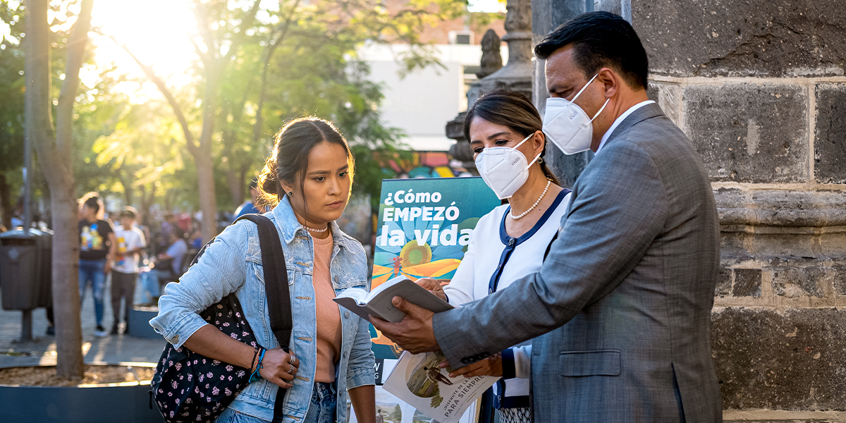 Un pareha testigo di Jehova ta predica cu garoshi di literatura; nan tin tapaboca bisti, y nan ta lesa un texto di Bijbel pa un mucha muher.