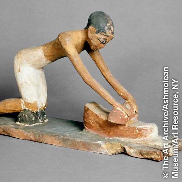 Un estatua di antiguo Egipto ta mustra con un hende ta mula grano