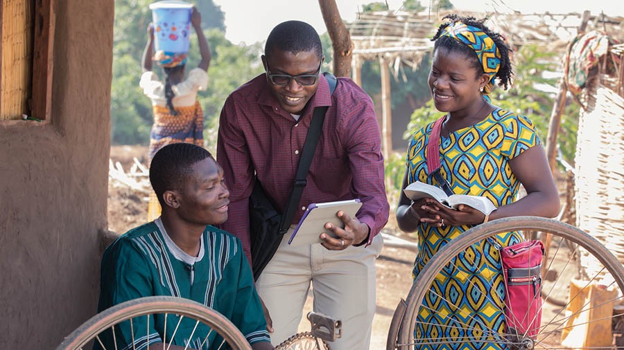 A Witness couple engaging in the field ministry. They are sharing a Bible-based video with a man.