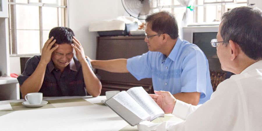 Two of Jehovah’s Witnesses comfort a fellow Christian