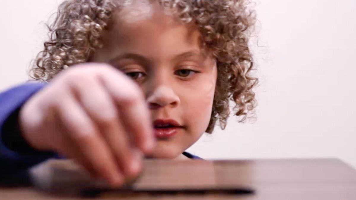 Uma menina põe um donativo numa caixa de donativos.