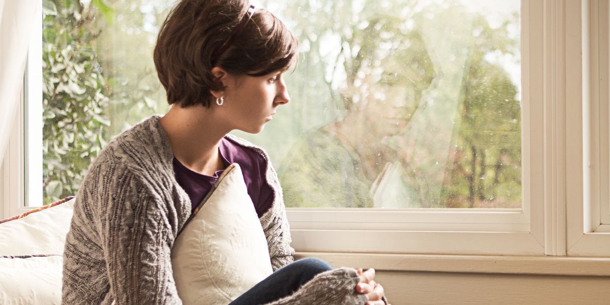 Una chica triste mirando por la ventana