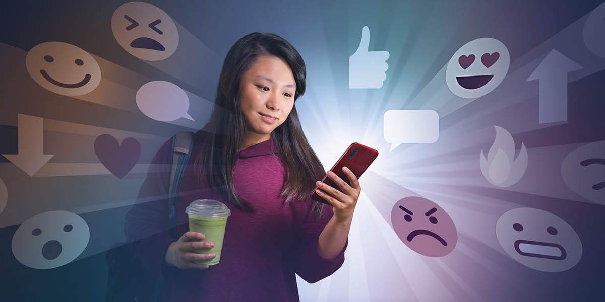 Una adolescente mira su celular. Se ven muchos emojis a su alrededor.