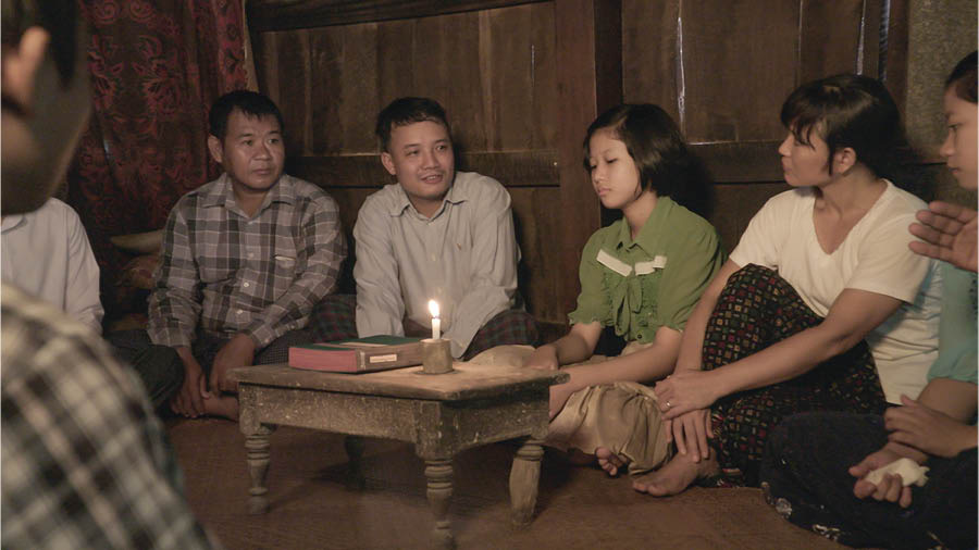 Una imagen del video Mostremos en la congregación el amor que nunca falla: A las viudas y a los huérfanos. Un grupito de hermanos consuela a la hermana Myint y a sus hijas en su casa después de que su esposo muriera en un accidente.