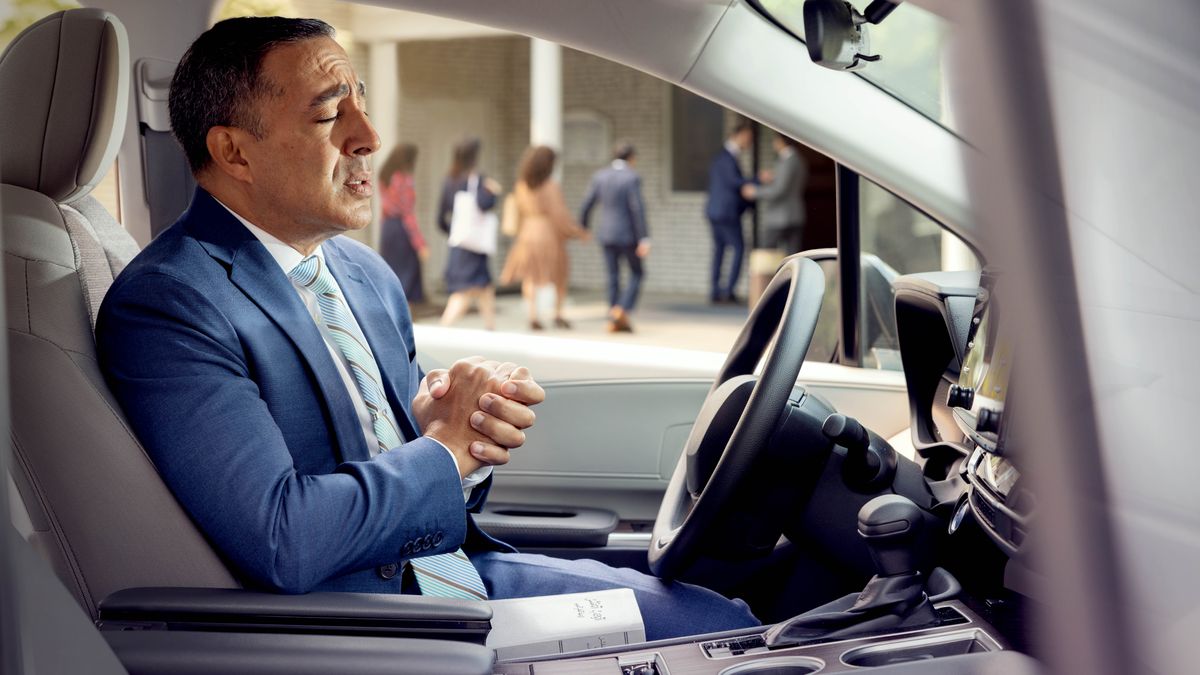 Un hombre que está expulsado ora en su auto antes de entrar al Salón del Reino.