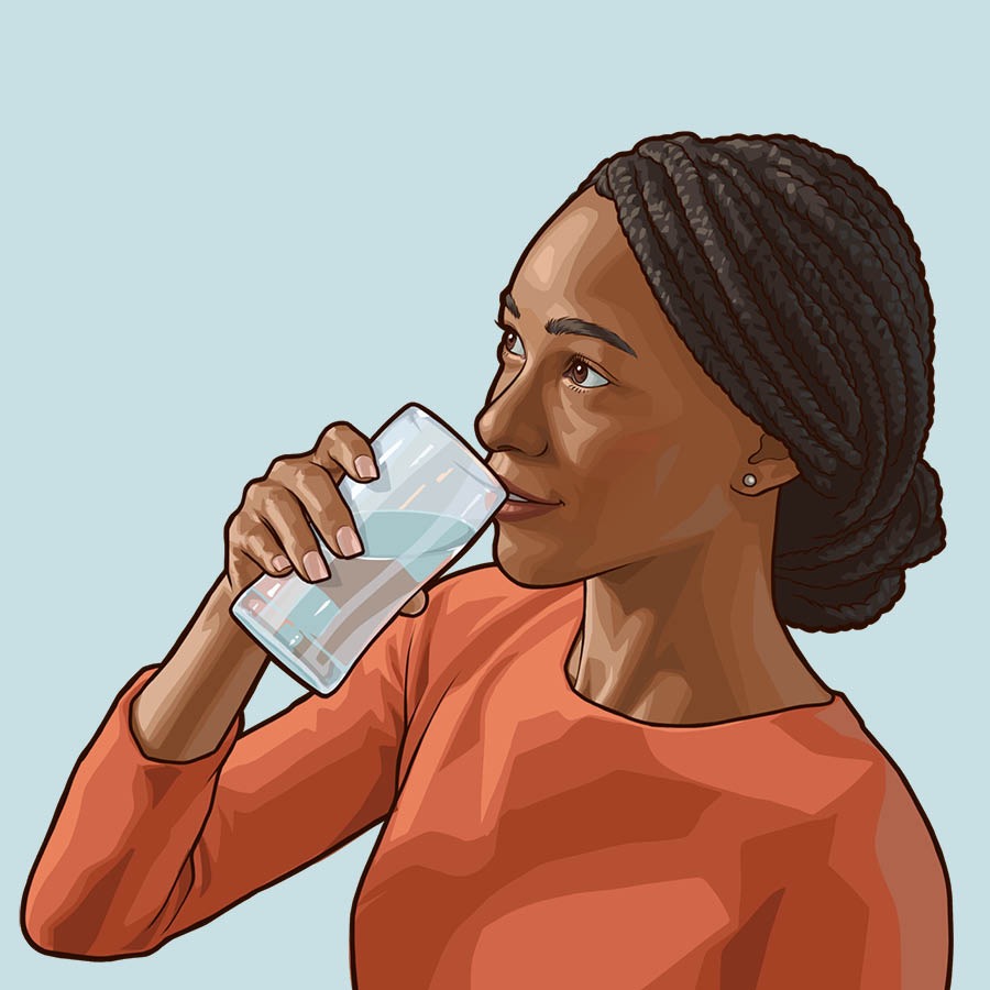 Una mujer bebe un vaso de agua.