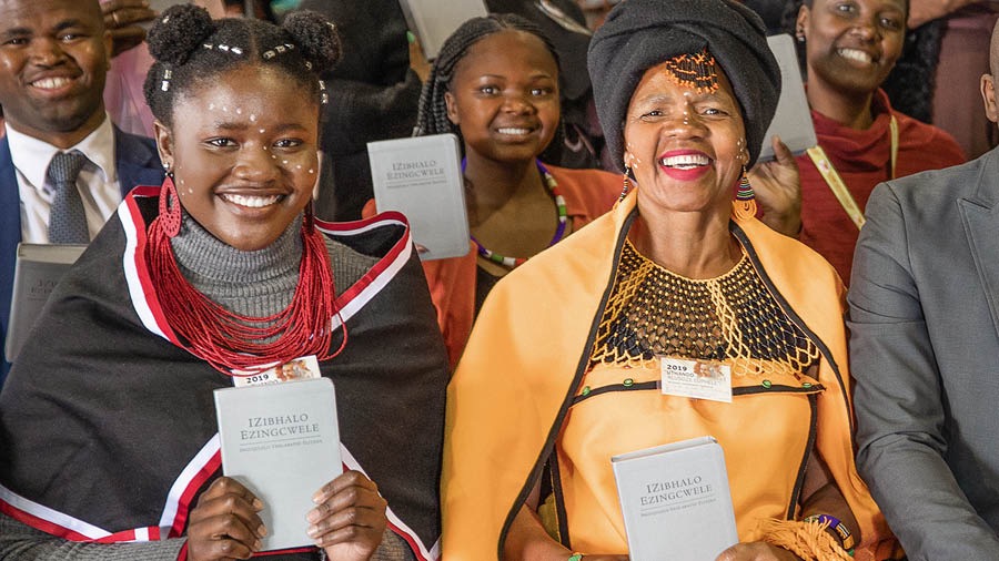 Unas hermanas y un hermano con la Traducción del Nuevo Mundo en xhosa recién publicada en sus manos.