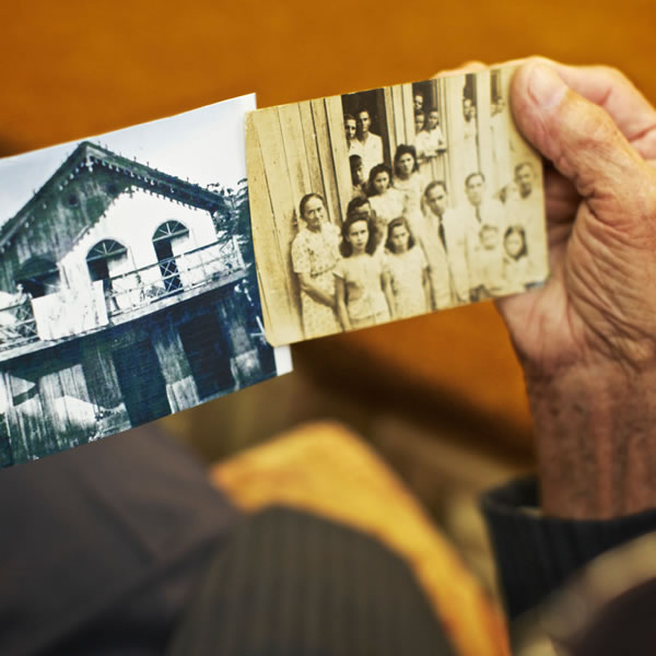 Антонью Симойнш держит две фотографии первого собрания в Манакири (штат Амазонас, Бразилия)