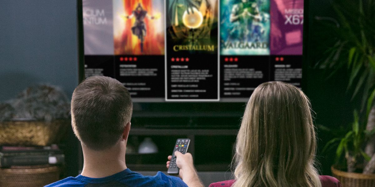 Umugabo n’umugore bariko bararaba urutonde rw’amasinema y’ivy’amashetani yerekanwa kuri televiziyo