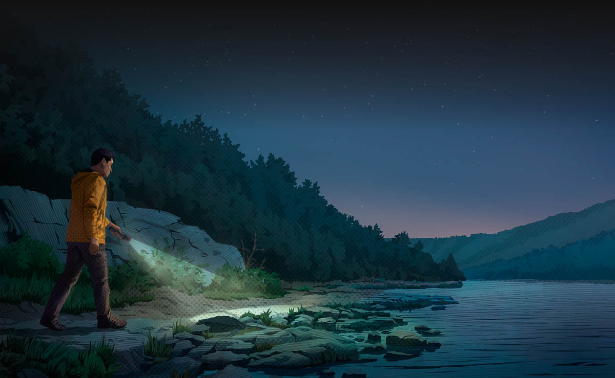 A man walking along the rocky shore of a lake at dusk, shining a flashlight on his path.
